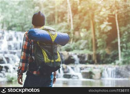 Traveling tourist man Backpack looking at amazing tropical mountains forest waterfall river. Travel Camping Hiking Journey holiday Concept. space for text, atmospheric moment summer vacations outdoor.