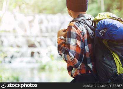 Traveling tourist man Backpack looking at amazing tropical mountains forest waterfall river. Travel Camping Hiking Journey holiday Concept. space for text, atmospheric moment summer vacations outdoor.