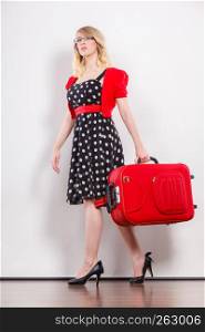 Traveling vacation concept. Elegant young woman in full length wearing polka dot black dress high heels with red suitcase ready for trip journey. Elegant fashion woman with red suitcase