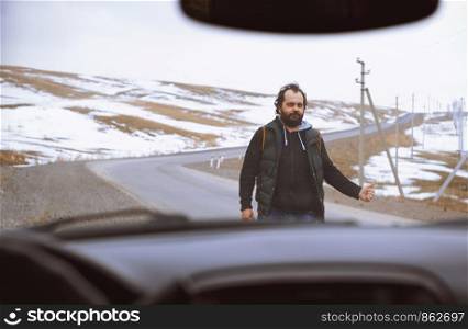 Traveller on the rural road trying to stop a car for assistance