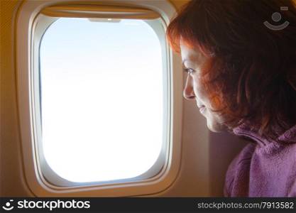 Travelling by air - woman is sitting in the airplane looking through window