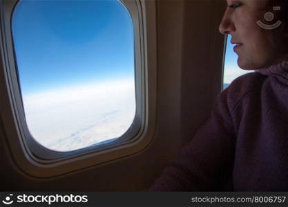 Travelling by air - woman is sitting in the airplane looking through window