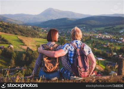 Travelling couple in love sitting on wooden bench with mountain view