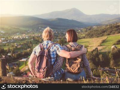 Travelling couple in love sitting on wooden bench with mountain view