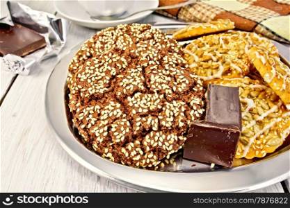 Tray with chocolate cookies and shortcake, chocolate, cup of tea, napkin on the background of bright boards