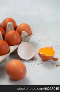 Tray with organic brown eggs with yolk on light background