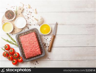 Tray with raw minced homemade beef meat with spices and herbs. Top view and space for text. On kitchen table background.