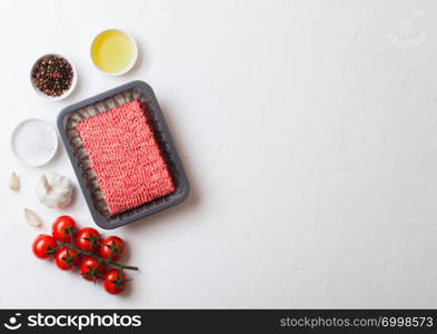 Tray with raw minced homemade beef meat with spices and herbs. Top view and space for text. On kitchen table background.