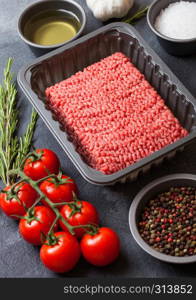 Tray with raw minced homemade beef meat with spices and herbs. Top view. On kitchen table background.