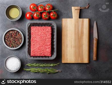 Tray with raw minced homemade beef meat with spices and herbs. Top view. On kitchen table background.