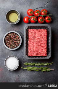 Tray with raw minced homemade beef meat with spices and herbs. Top view. On kitchen table background.