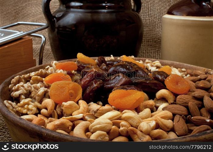 Tray with walnuts, almonds, cashews, dates and apricots in a rustik setting with stoneware