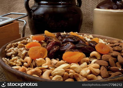 Tray with walnuts, almonds, cashews, dates and apricots in a rustik setting with stoneware