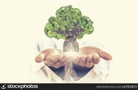 Tree of gears. Environmental concept with hand hold green tree of industrial gear