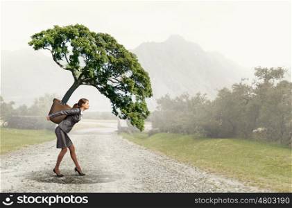 Tree of success. Businesswoman carrying plant in pot on her back