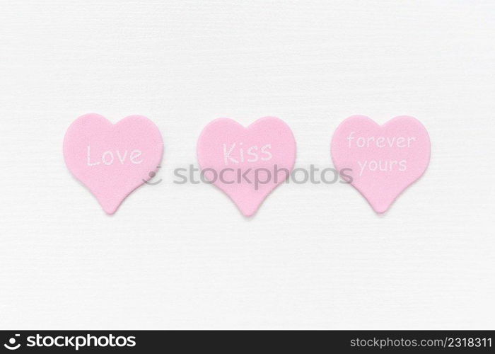 Tree pink hearts with text LOVE, KISS, FOREVER YOURS on white background with copy space. Valentines day concept. Gift for lover, love confession. Top view Flat lay Minimal style.. Tree pink hearts with text LOVE, KISS, FOREVER YOURS on white background with copy space. Valentines day concept. Gift for lover, love confession. Top view Flat lay Minimal style