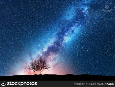 Trees against starry sky with Milky Way. Space background. Night landscape with alone trees on the hill and colorful bright milky way. Amazing galaxy. Nature. Beautiful scene with universe. Concept