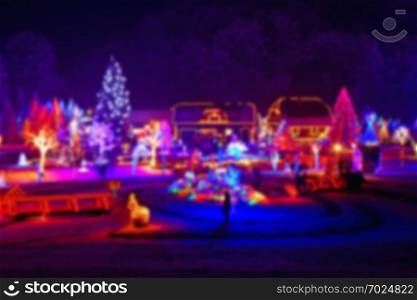 Trees and houses in christmas lights blurred view on beautiful snowy winter night