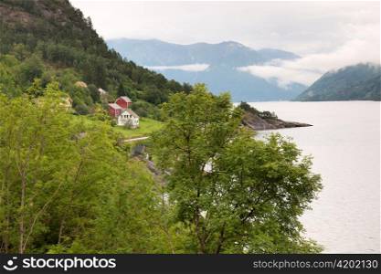 Trees at coast with houses in the background, Hardanger, Hardangerfjord, Hardangervidda, Hardanger, Norway