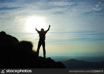 Trekker silhouette at the summit of his climb