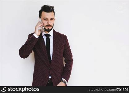 Trendy and fashionable businessman posing on a white background and talking on the phone.