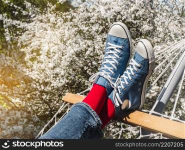 Trendy boots and colorful socks on the background of a flowering tree. Close-up, outdoor. Day light. Men&rsquo;s and women&rsquo;s style. Beauty and elegance concept. Trendy boots and colorful socks. Day light