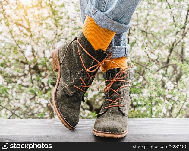 Trendy boots and colorful socks on the background of a flowering tree. Close-up, outdoor. Day light. Men&rsquo;s and women&rsquo;s style. Beauty and elegance concept. Trendy boots and colorful socks. Day light