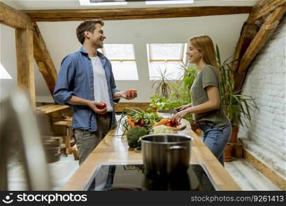 Trendy couple peeling and cutting vegetables from the market in rustic kitchen
