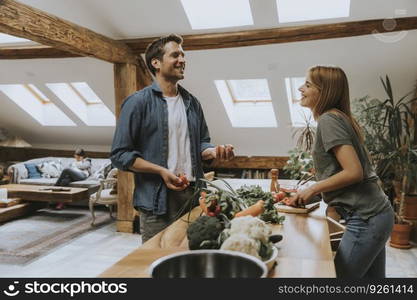 Trendy couple peeling and cutting vegetables from the market in rustic kitchen