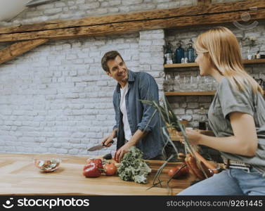 Trendy couple peeling and cutting vegetables from the market in rustic kitchen