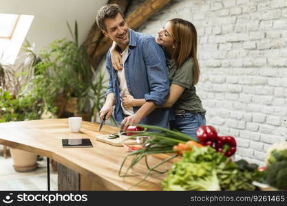 Trendy couple peeling and cutting vegetables from the market in rustic kitchen