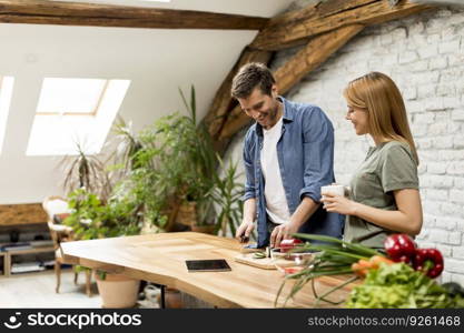 Trendy couple peeling and cutting vegetables from the market in rustic kitchen