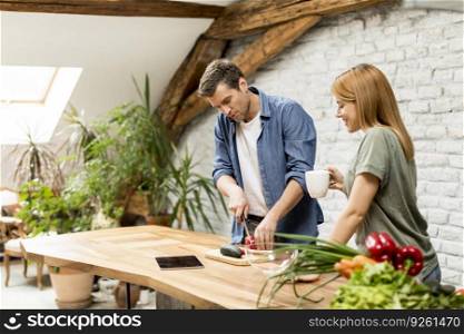 Trendy couple peeling and cutting vegetables from the market in rustic kitchen