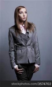Trendy fashion model posing in grey costume. Studio shot