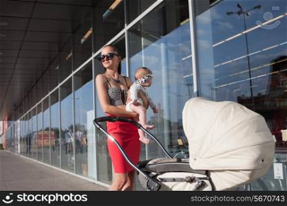 Trendy mother and baby posing near showcase
