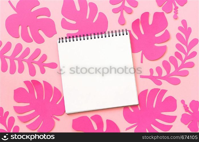 Trendy pink tropical leaves of paper and open notebook on pink background. Flat lay, top-down composition, creative paper art.. Trendy pink tropical leaves of paper and open notebook on pink background. Flat lay, top-down composition, creative paper art