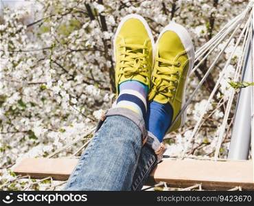 Trendy sneakers and colorful socks on the background of flowering trees. Closeup, outdoors. Men&rsquo;s and women&rsquo;s fashion style. Beauty and elegance concept. Trendy sneakers and colorful socks. Closeup, outdoors