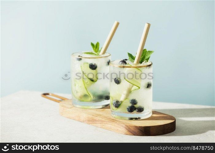 Trendy summer drinks with cucumber, mint and blueberry on blue sky background. Trendy summer drinks with cucumber, mint and blueberry