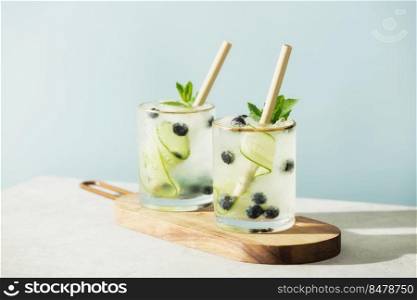 Trendy summer drinks with cucumber, mint and blueberry on blue sky background. Trendy summer drinks with cucumber, mint and blueberry