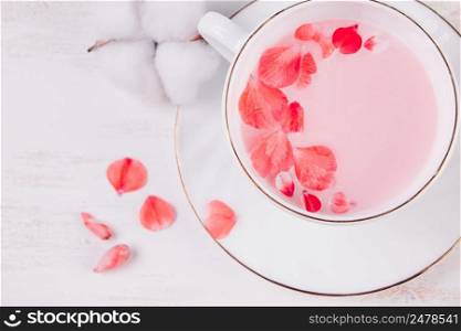 Trendy vegan tea on a white background. Pink matcha with rose petals in a cup. Relaxing drink recipe for sleepy times.. Trendy vegan tea on white background. Pink matcha with rose petals in a cup. Relaxing drink recipe for sleepy times.