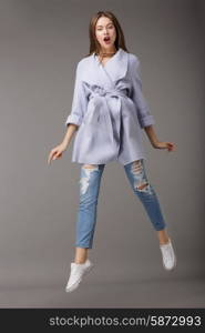Trendy Young Female Jumping in Blue Coat