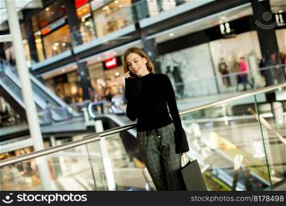 Trendy young woman shopping in mall and using mobile phone
