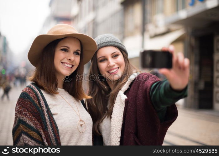 Trendy young women taking selfies in the city