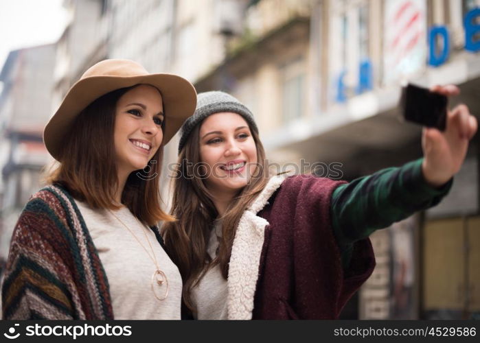 Trendy young women taking selfies in the city