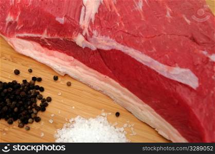 Tri Tip Roast And Species. Fresh raw tri-tip roast with fat marbled through the meat ready to roast or barbeque with sea salt, black peppercorns, herbs and garlic cloves