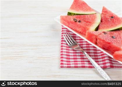 Triangle slices of watermelon on the plate on white wooden background. Top view, flat lay, mockup with copy space for text. Sliced watermelon on the plate on white wooden background