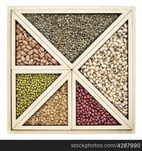 triangles and squares abstract - a variety of beans and lentils in an isolated wooden tray