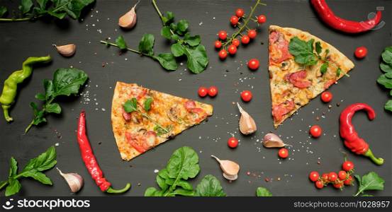 triangular piece of baked pizza with mushrooms, smoked sausages, tomatoes and cheese, black background, flat lay