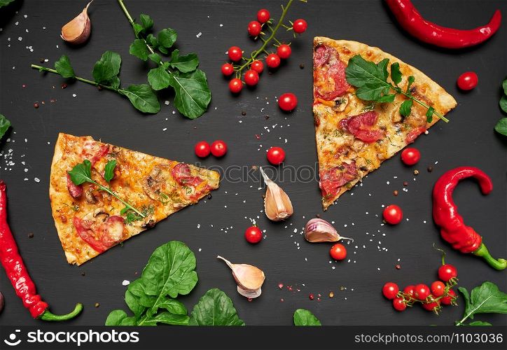 triangular piece of baked pizza with mushrooms, smoked sausages, tomatoes and cheese, black background, flat lay