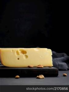 triangular piece of maasdam cheese on a brown wooden board
